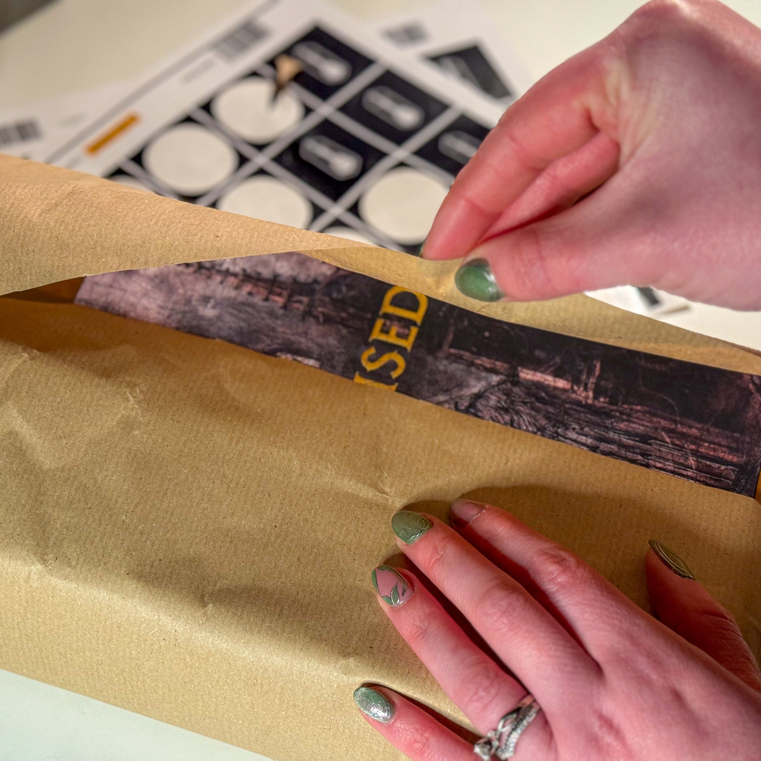 Person unrolling brown paper with a label on a light-colored surface